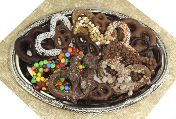 Chocolate covered pretzels in a silver tray, atop a gold pattern background